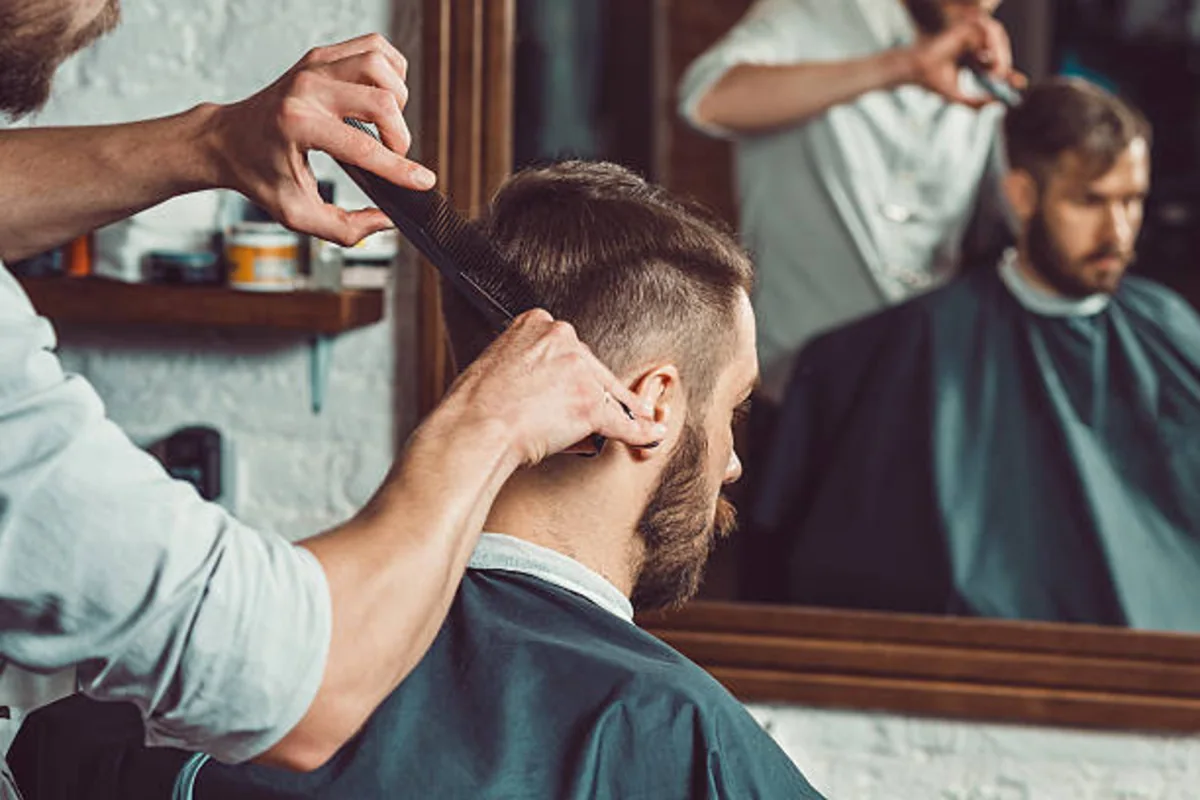 Un barbero terminando el corte de un cliente